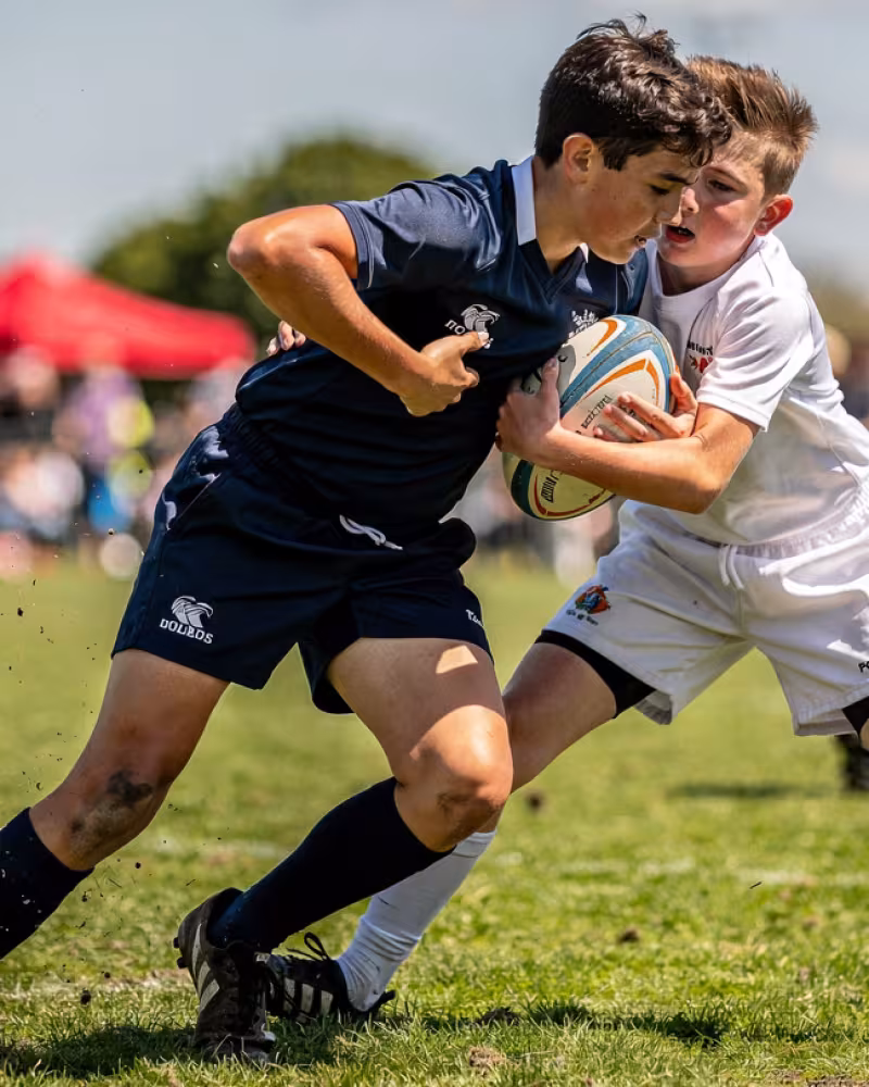 Youth rugby player breaking through a tackle during a rugby festival match