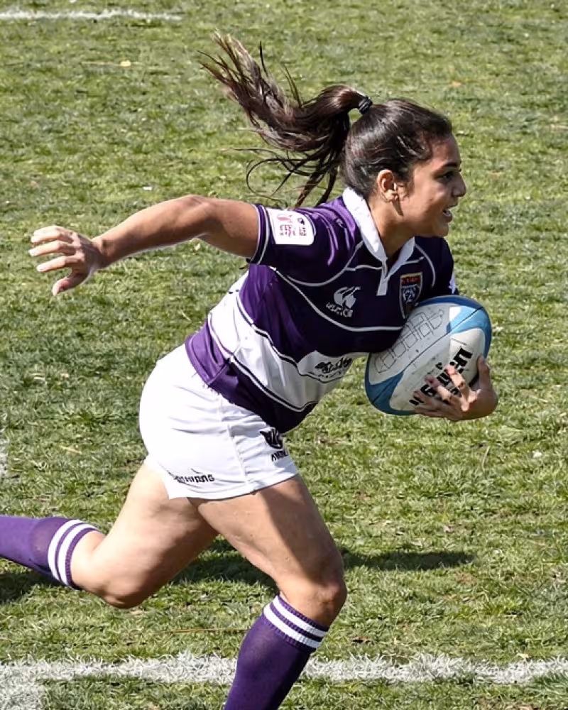 Teenage girls competing for the ball during a rugby sevens match