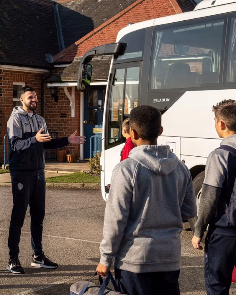 Youth rugby team in tracksuits boarding a coach outside their home club