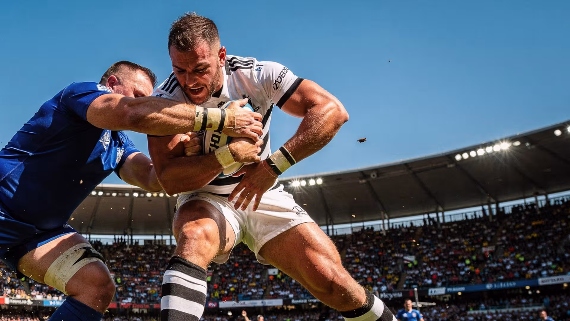 A rugby player being tackled head-on during a professional match at a packed stadium