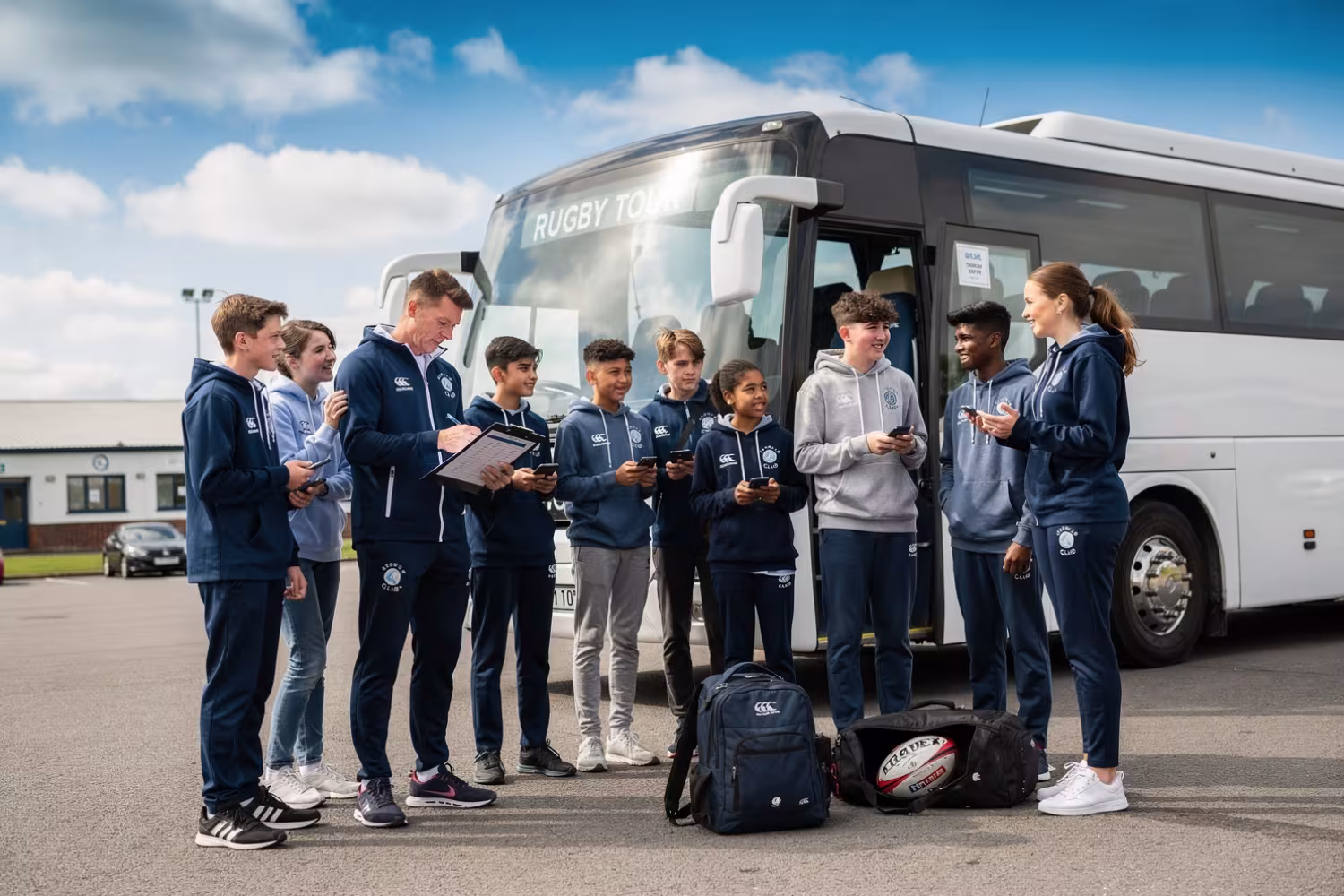 Youth rugby team and coaches in travelwear outside a modern touring coach